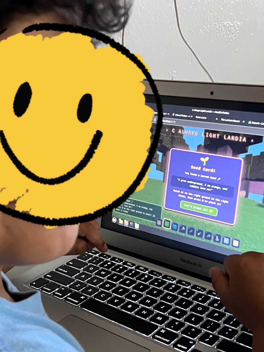 My son playtesting C Always Light Landia on a laptop, his face covered by a smiley